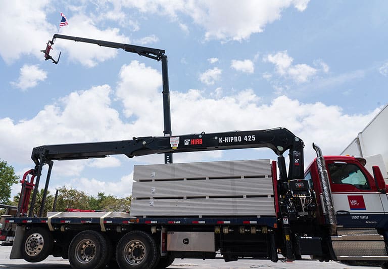 L&W Supply truck displaying an elevated American flag from its crane arm.