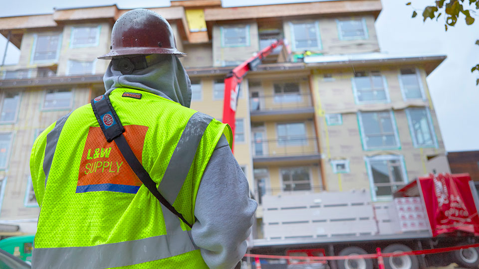 Figure in a L&W Supply Yellow Safety Vest Overseeing a Delivery